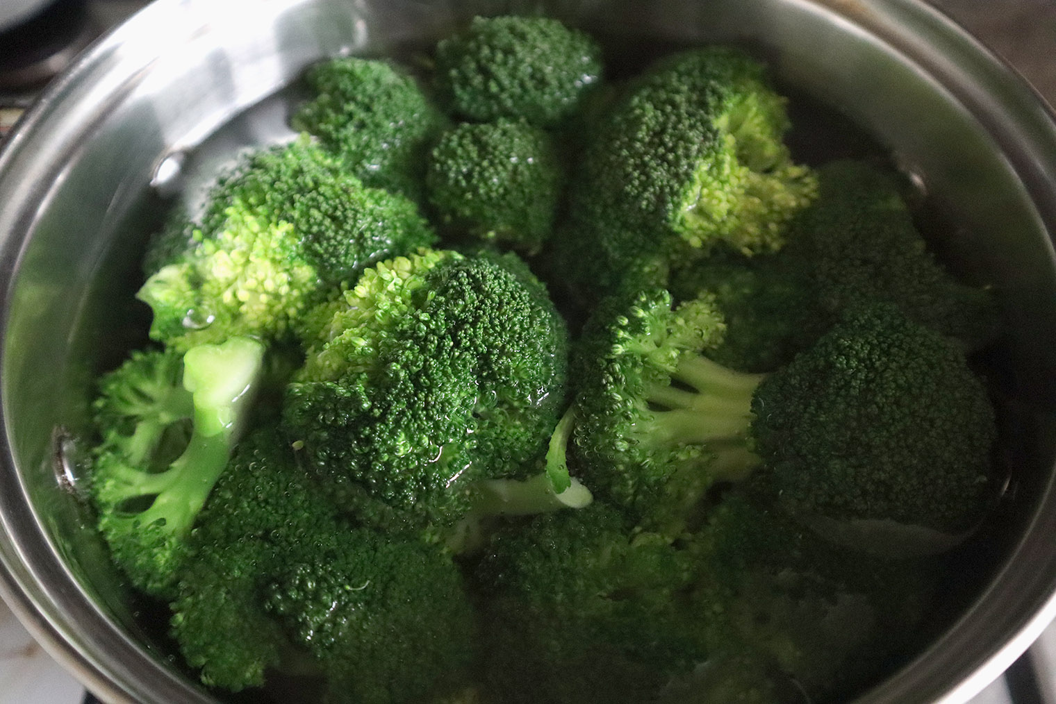 Шаг 2. Налейте в кастрюлю такое количество воды, чтобы она покрывала брокколи, но пока не кладите капусту. Воду доведите до кипения, посолите из расчета 1/2—1 ст. л. соли на литр воды. Брокколи опустите в кипящую воду. Если хотите более хрусткую текстуру, варите 2 минуты, для более мягкой — 3 минуты. Чтобы понять, устраивает ли вас жесткость брокколи, проткните пару соцветий ножом