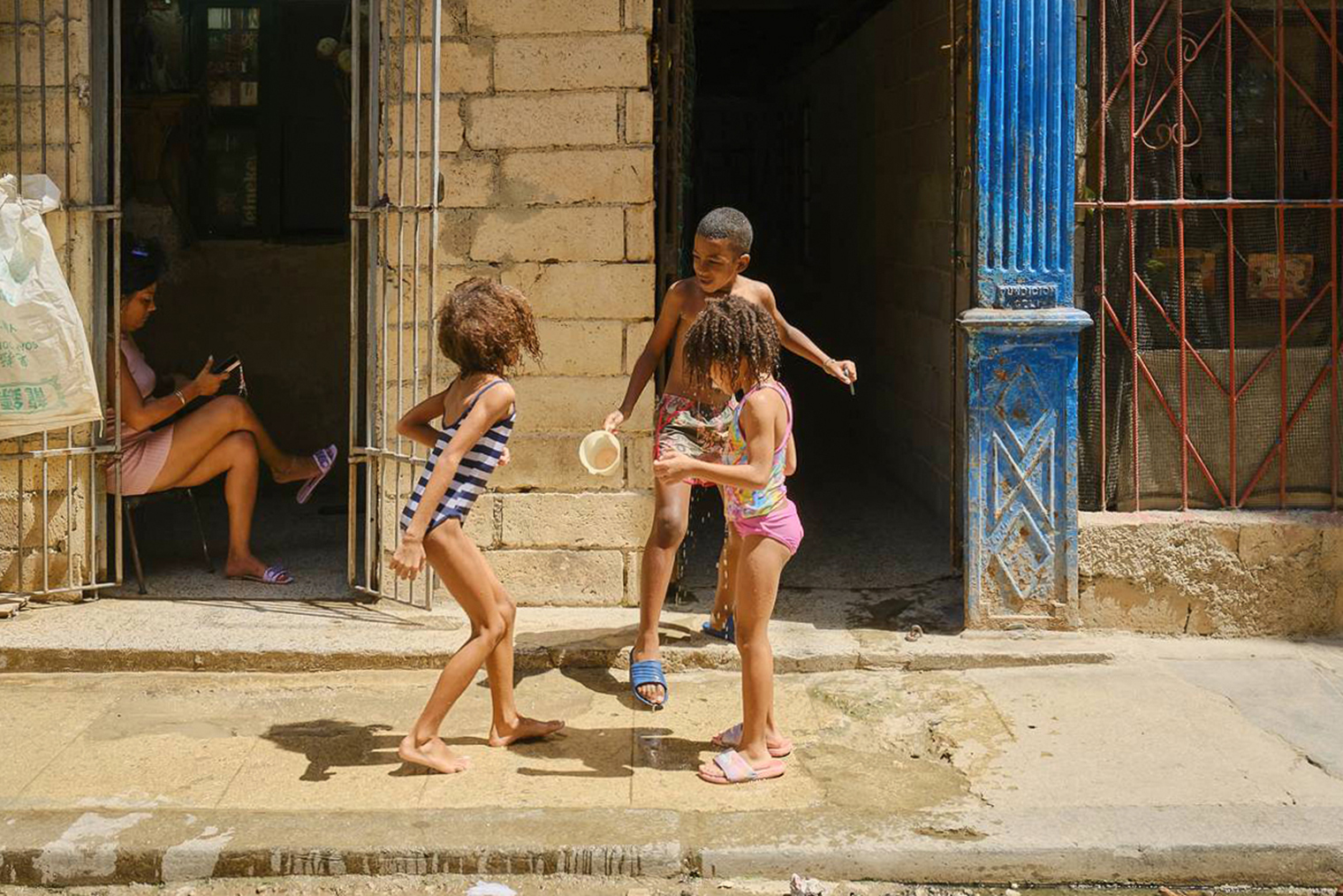 В Старой Гаване теснее и больше людей, а на окраинах улицы зачастую превращаются в место, чтобы поиграть в догонялки, футбол или баскетбол. На фото — игры детей из Старой Гаваны. Паренек окатил холодной водой одну из девочек, чем спровоцировал небольшой скандал