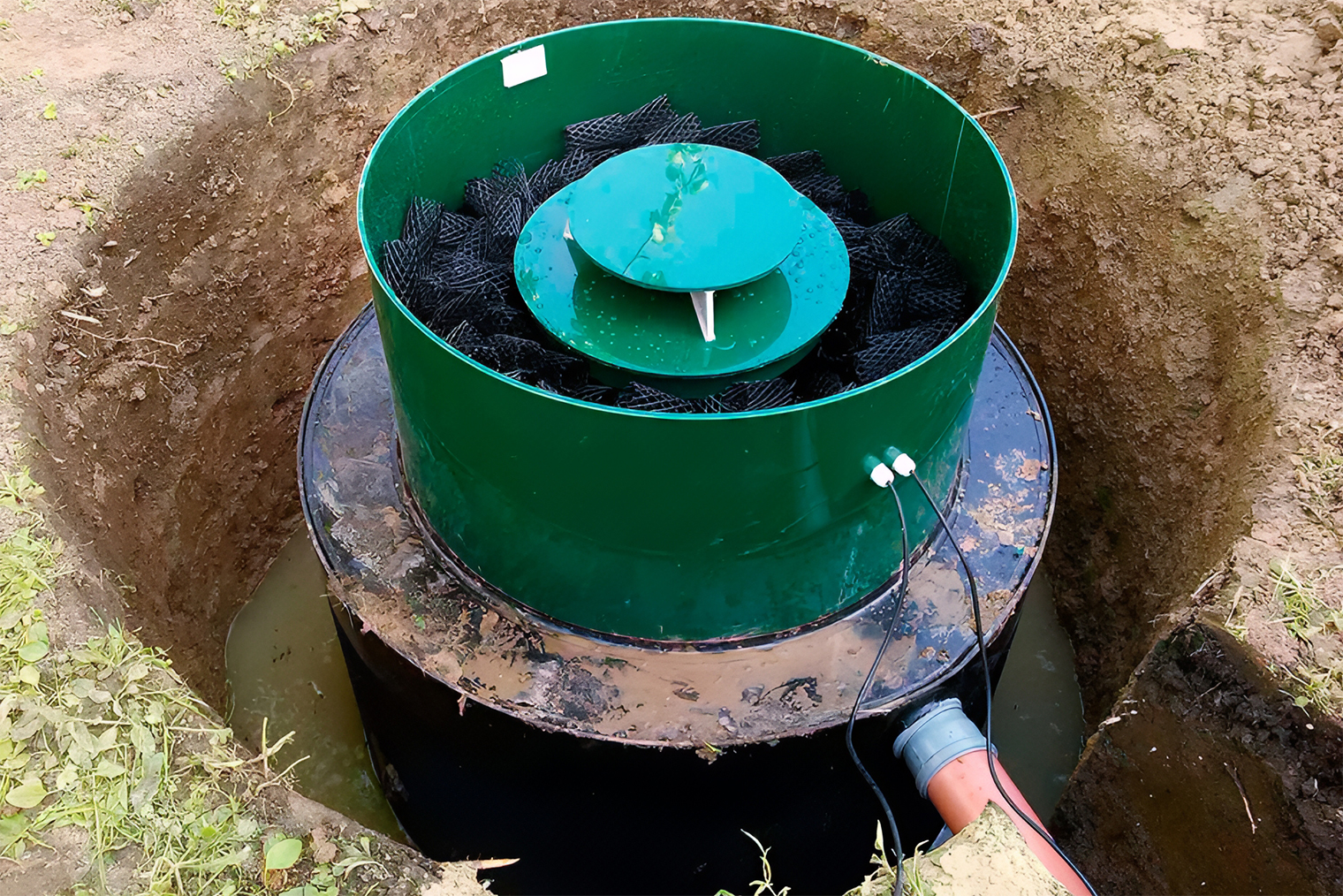 Станции очистки часто изготавливают в виде вертикальной емкости. Сверху видна специальная биозагрузкаБиозагрузка — пластиковые «мочалки» внутри станции, которые нужны для бактерий. Бактерии живут в них и очищают стоки, через которую дополнительно проходят стоки. К станции подведено электричество для аэрации — питания бактерий кислородом. © Станислав Мирошенко