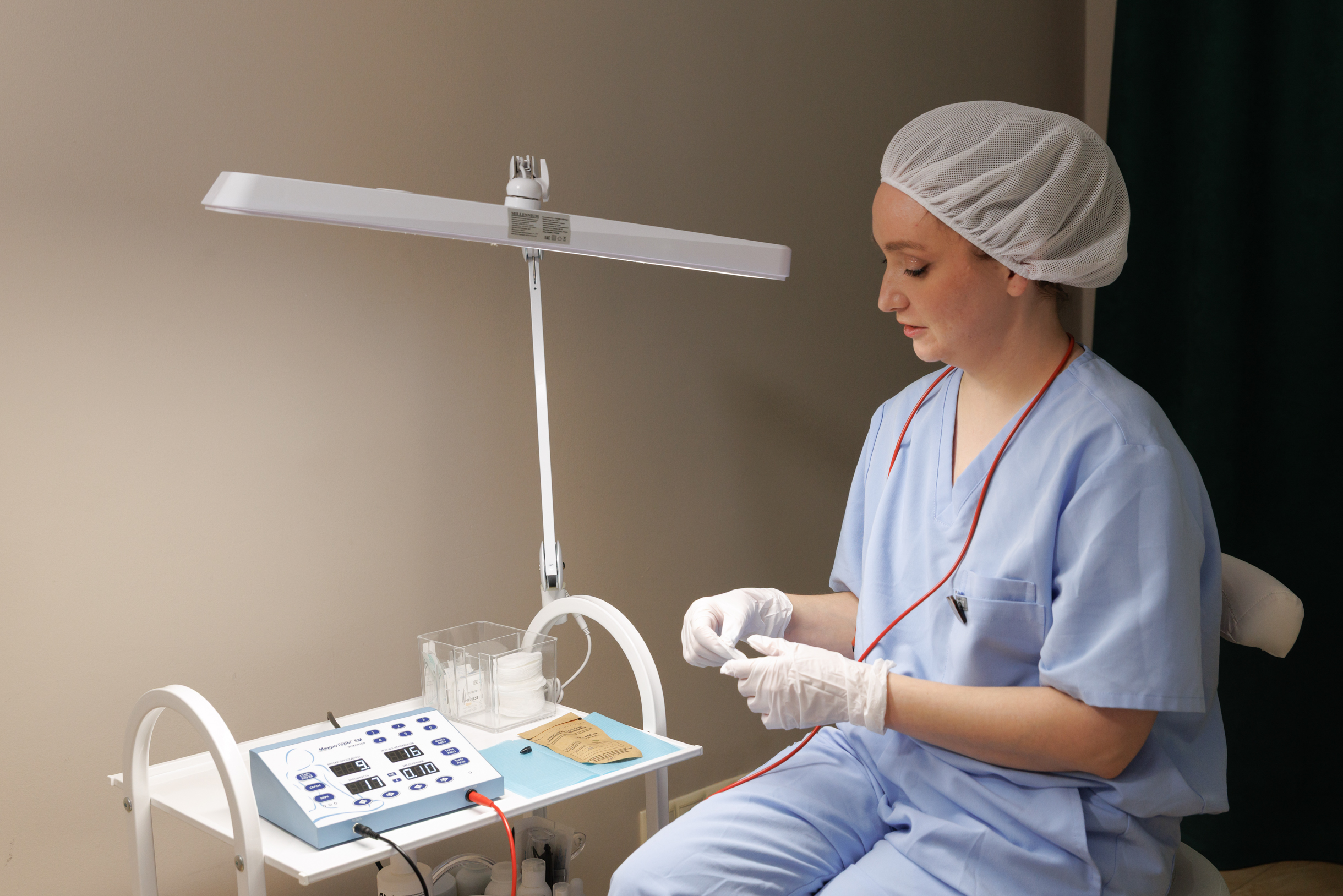 Рабочее место мастера — аппарат для электроэпиляции, лампа-лупа, стерильные инструменты и расходники для процедуры