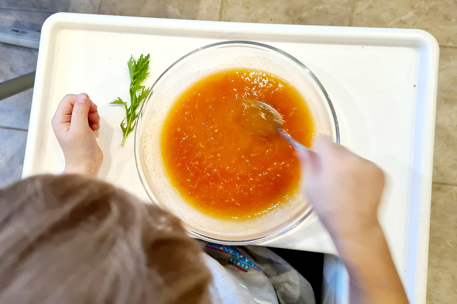 Сын смешивает красный суп-пюре из томатов с бледно-желтым из цветной капусты
