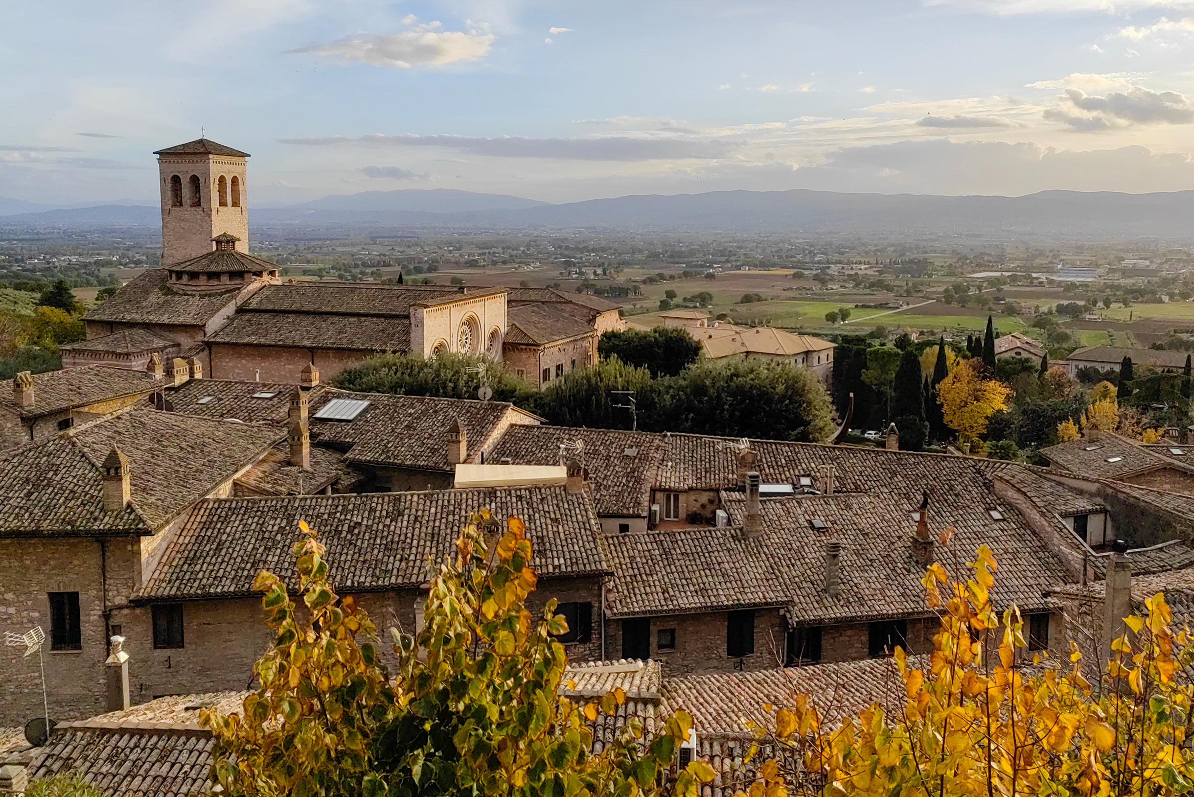 Пейзаж с высоты города Ассизи. Теплый солнечный цвет на закате подчеркивал цвет осенних листьев