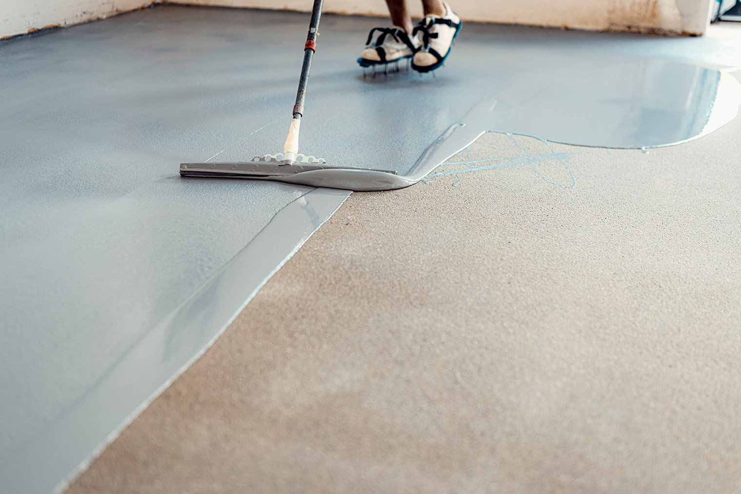 Выравнивание основания самонивелирующейся смесью в большом помещении. Это жидкий раствор, который, растекаясь по полу, образует гладкое и ровное основание © Doralin Samuel Tunas / Shutterstock / FOTODOM