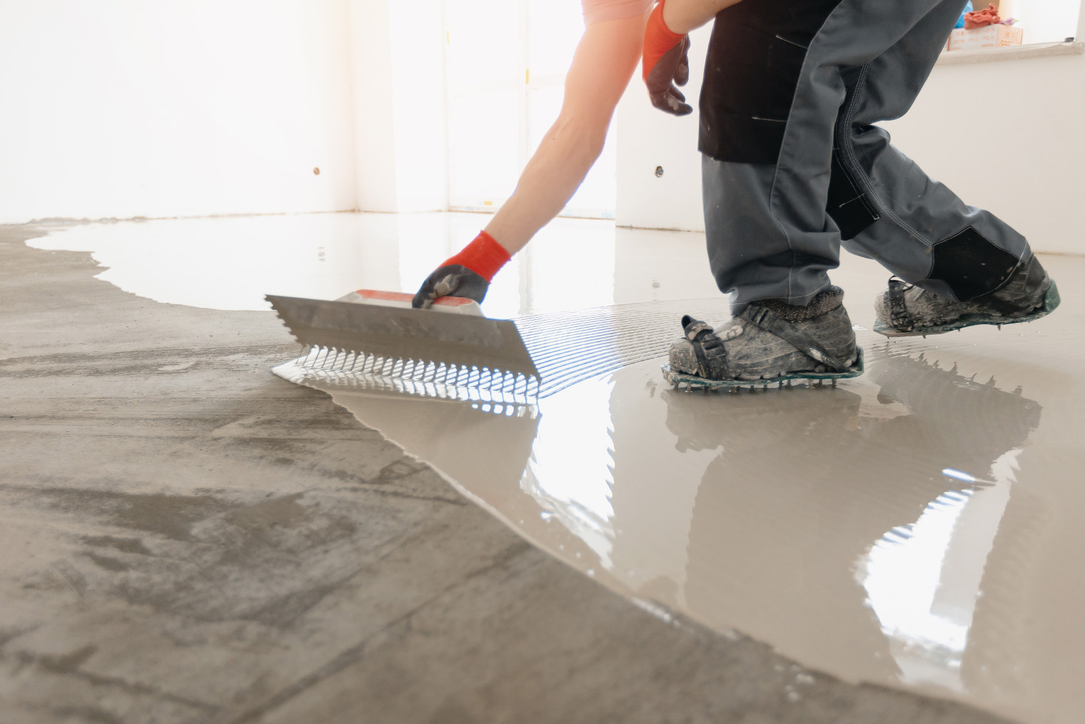 На деревянный пол ровнитель заливают так же, как и на бетонный, только предварительно заделывают все щели, а по периметру фиксируют демпферную ленту толщиной 10 мм, чтобы обеспечить эластичность всей поверхности. Если это пол из обрезной доски и щелей слишком много, доски застилают изолирующим материалом, например «Пенофолом», с нахлестом на стену — заводят его под демпферную ленту. Фотография: Parilov / Shutterstock / FOTODOM