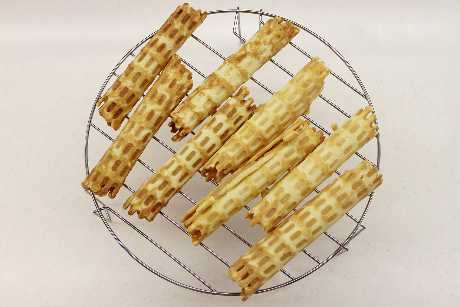 Шаг 7. Повторите шаги с оставшимся тестом. В идеале остужать трубочки на решетке — так они будут более хрустящими. Если ее нет, выкладывайте горячие вафли на тарелку не слишком плотно друг к другу