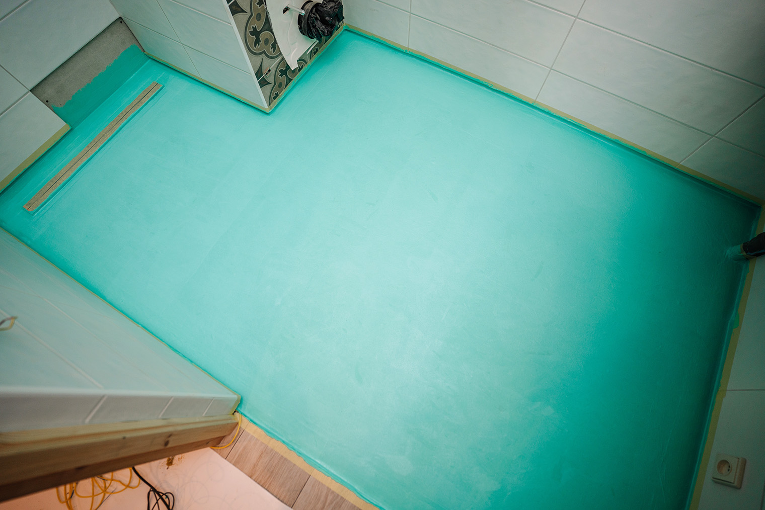 Обычно производители выпускают полимерную обмазочную гидроизоляцию в нескольких цветах, чтобы при нанесении в несколько слоев было видно, какие участки не промазаны дважды. Так будет выглядеть пол в ванной перед укладкой плитки. Обратите внимание, что гидроизоляция заходит на стены © shulers / Shutterstock / FOTODOM