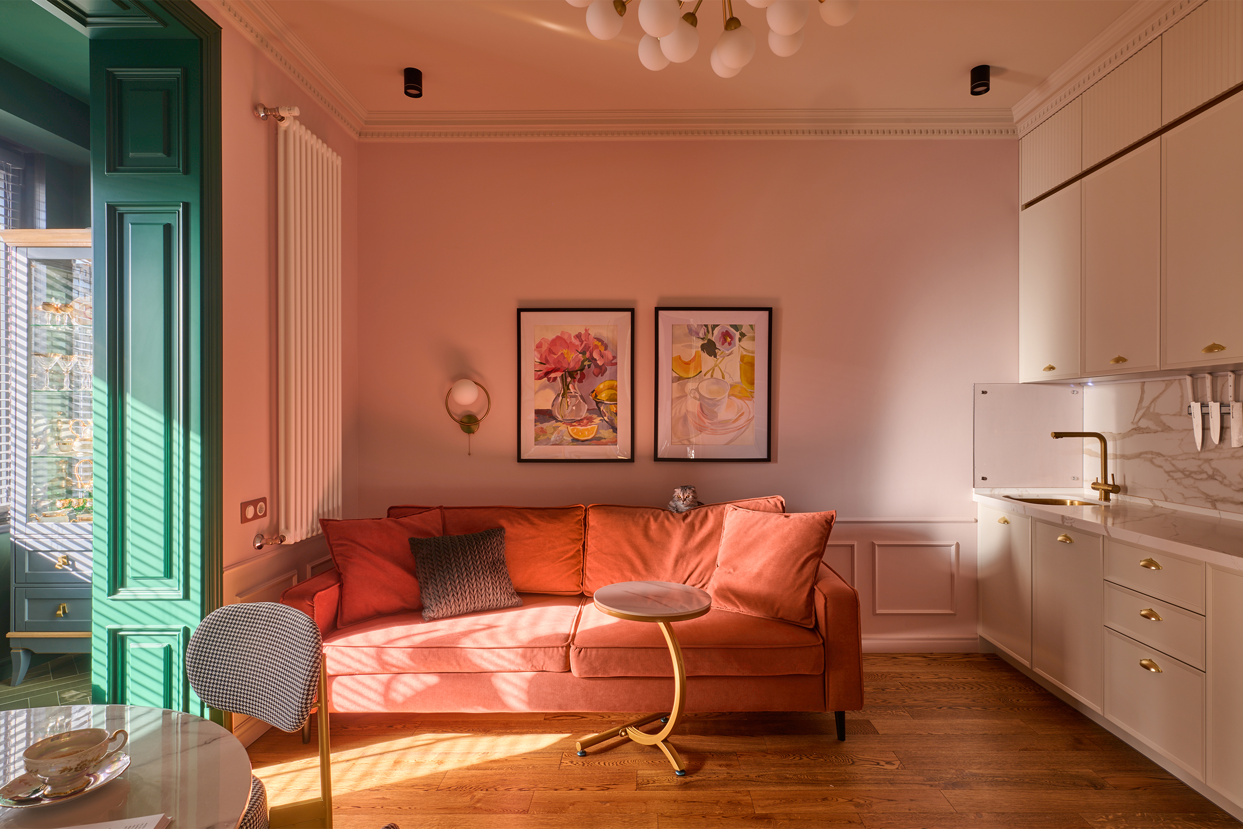 В гостиной много архитектурного декора, который делает стены нескучными: широкий карниз, который закрывает щель между гарнитуром и потолком, молдинги в рамках на стене, панели в портале между комнатой и балконом