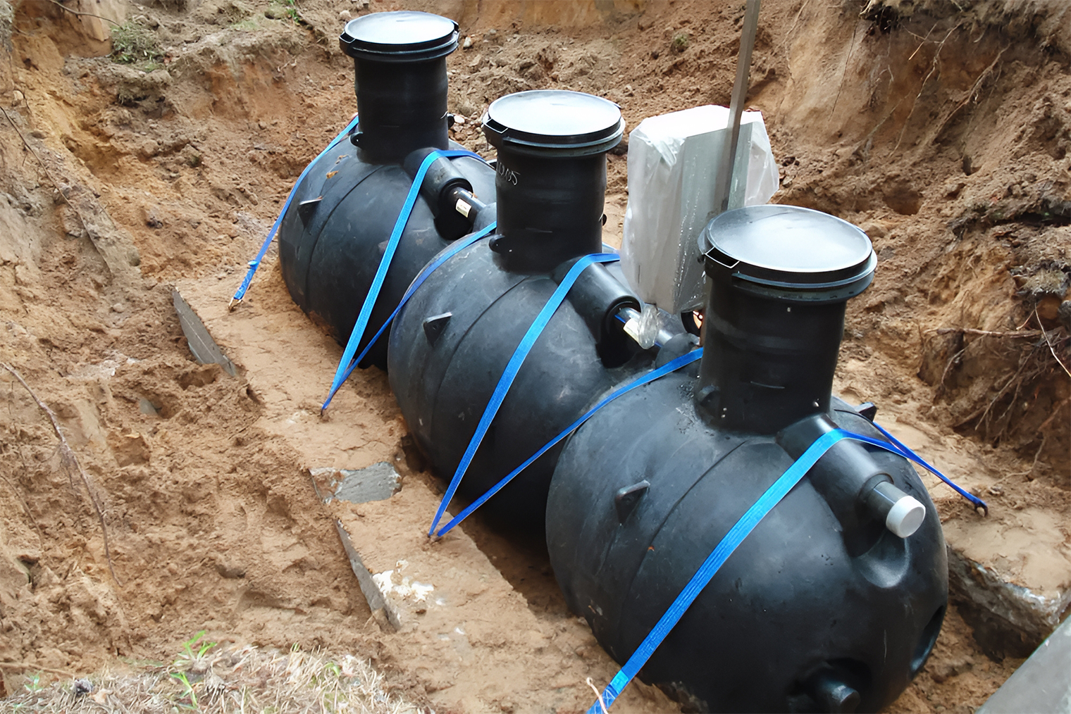 Трехкамерный энергонезависимый септик с крепежом к бетонным блокам. Ремни натянуты, чтобы по весне, когда в грунте будет вода, бочки не всплыли на поверхность. © Станислав Мирошенко