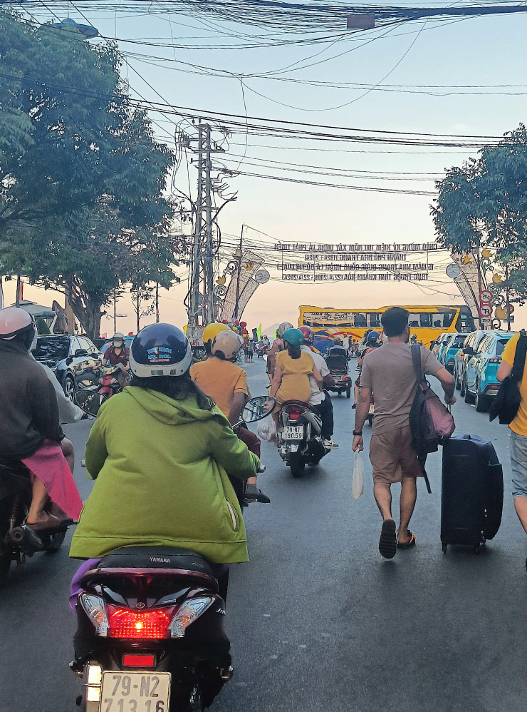 По одной дороге едут машины и байки, а рядом идут туристы с чемоданами — это норма для Вьетнама