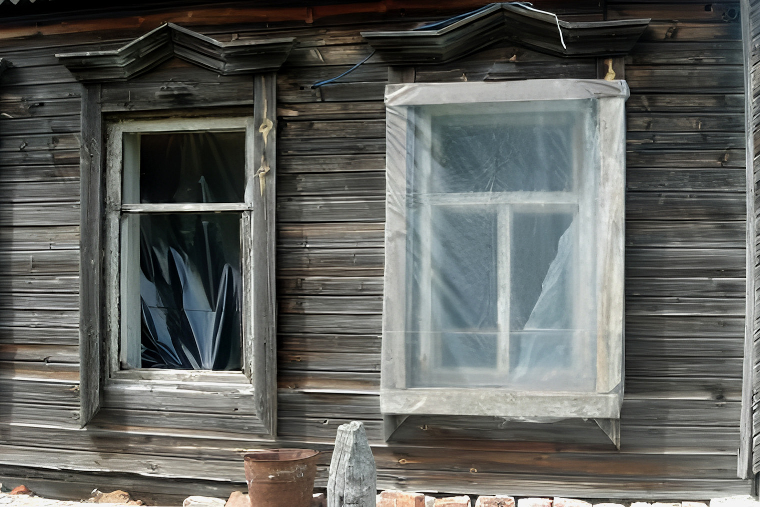 Это вряд ли жилой дом, но принцип утепления окна — такой. По аналогии с рольставнями пленка, набитая снаружи рамы, создает неподвижную воздушную прослойку, а воздух — отличный теплоизолятор. Поэтому способ реально работает. При необходимости, например когда окна на большой высоте, пленку можно прибить к раме изнутри