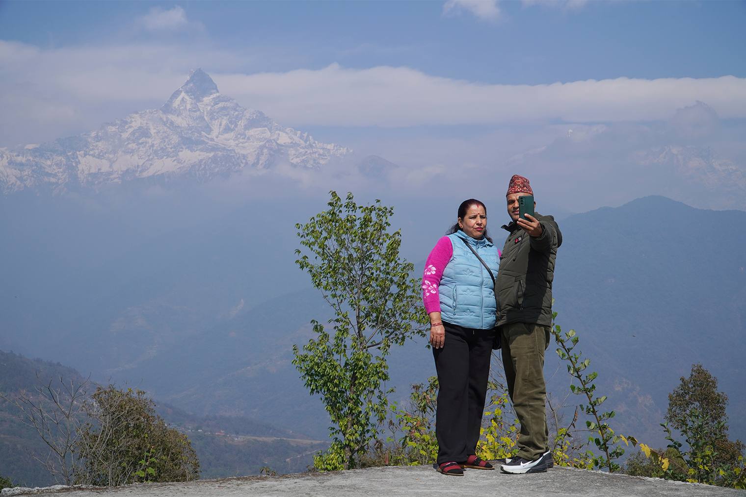 Непальцы фотографируются на фоне священной горы Мачапучаре