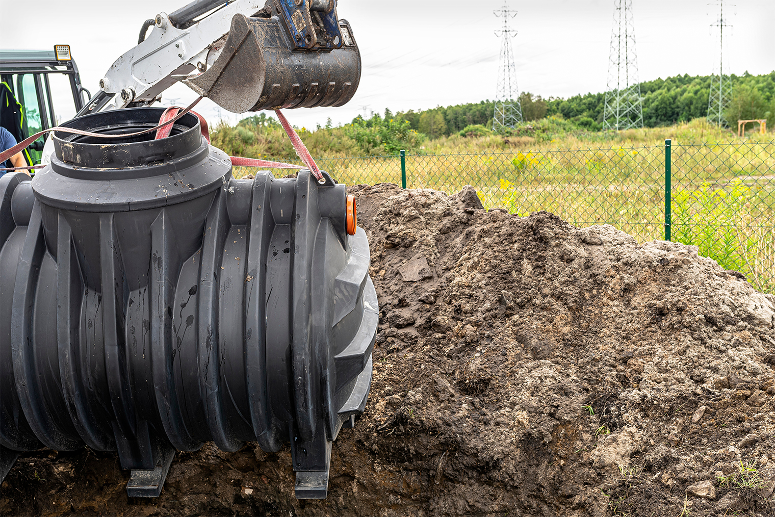 Пластиковую емкость можно опустить в яму и вручную, но если на участке уже работает трактор, проще задействовать его. © Kinek00 / Shutterstock / FOTODOM