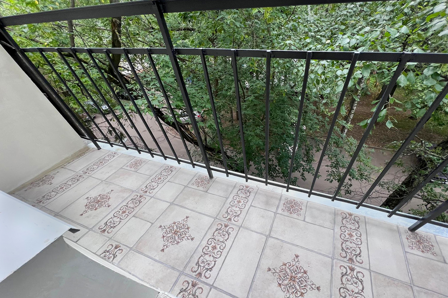 Обновленный балкон: мастер положил плитку, а решетку покрасил в черный цвет