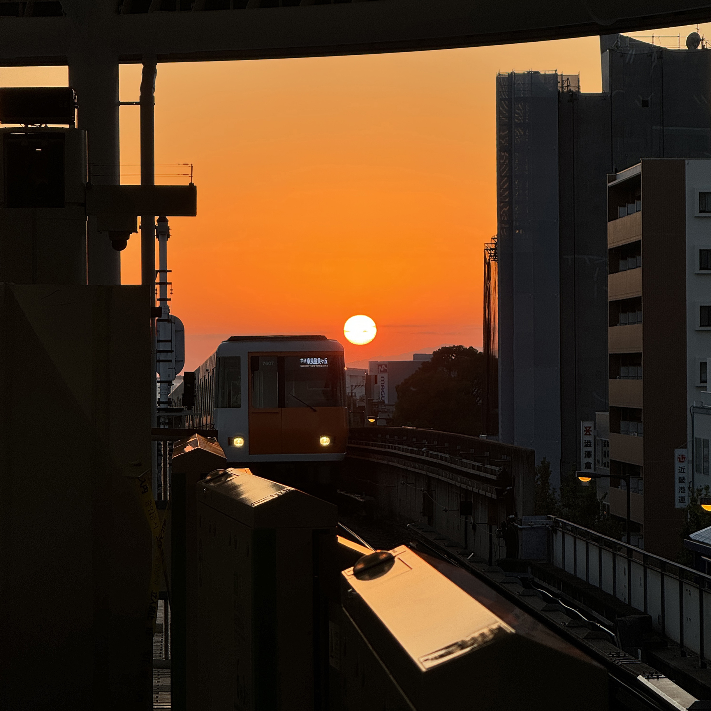 Закат на окраине Осаки на фоне поезда метро. В центре из-за плотной застройки станции чаще подземные, но есть и надземные