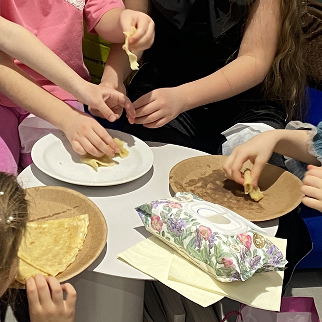 Дочь ест блины на детском празднике