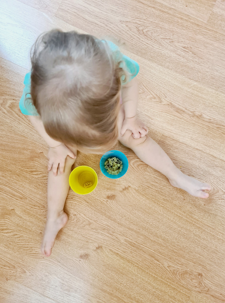 Дочка перекладывает макароны в форме игрушек из одного стакана в другой