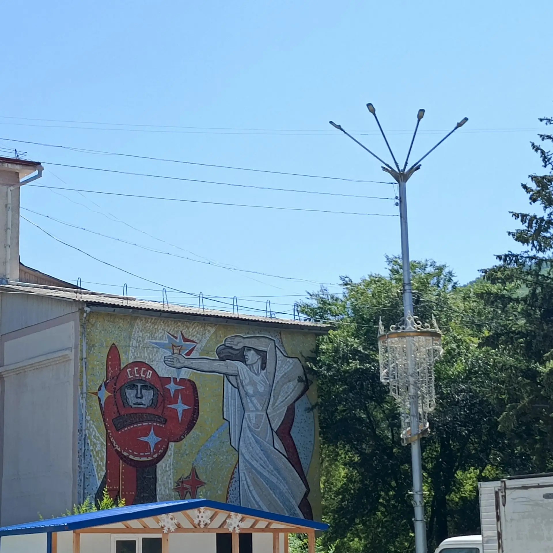 Площадь на реконструкции и на ней сохранилось новогоднее убранство). Фреска на здании — советское наследие — издалека притягивает взгляд.