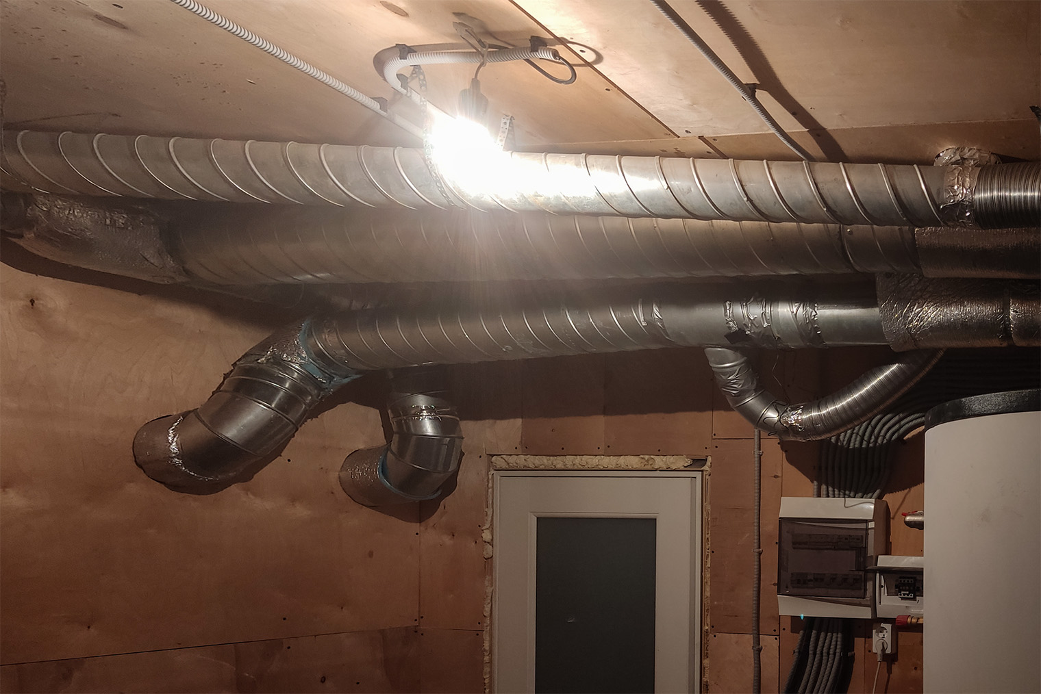 Так выглядит разводка вентиляции под потолком котельной. Сами вентиляторы, рекуператор, шумоглушители, воздушный фильтр — в пристройке, которая расположена через стену позади дома