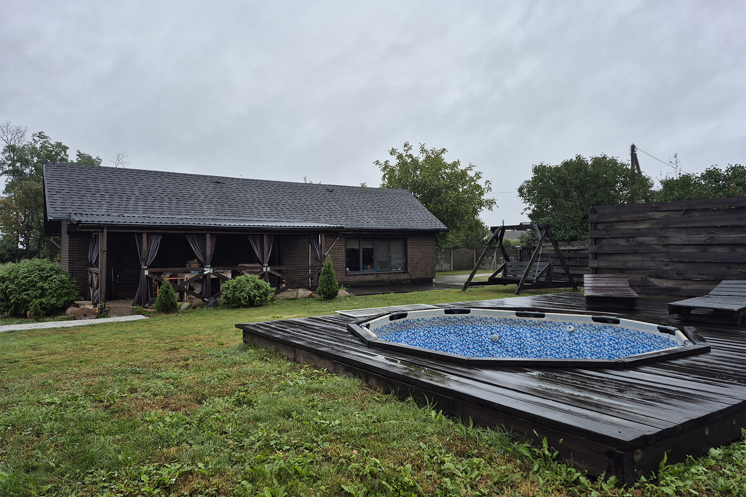 Участок мы обустроили. Кроме качелей поставили деревянный настил с шезлонгами и каркасный бассейн