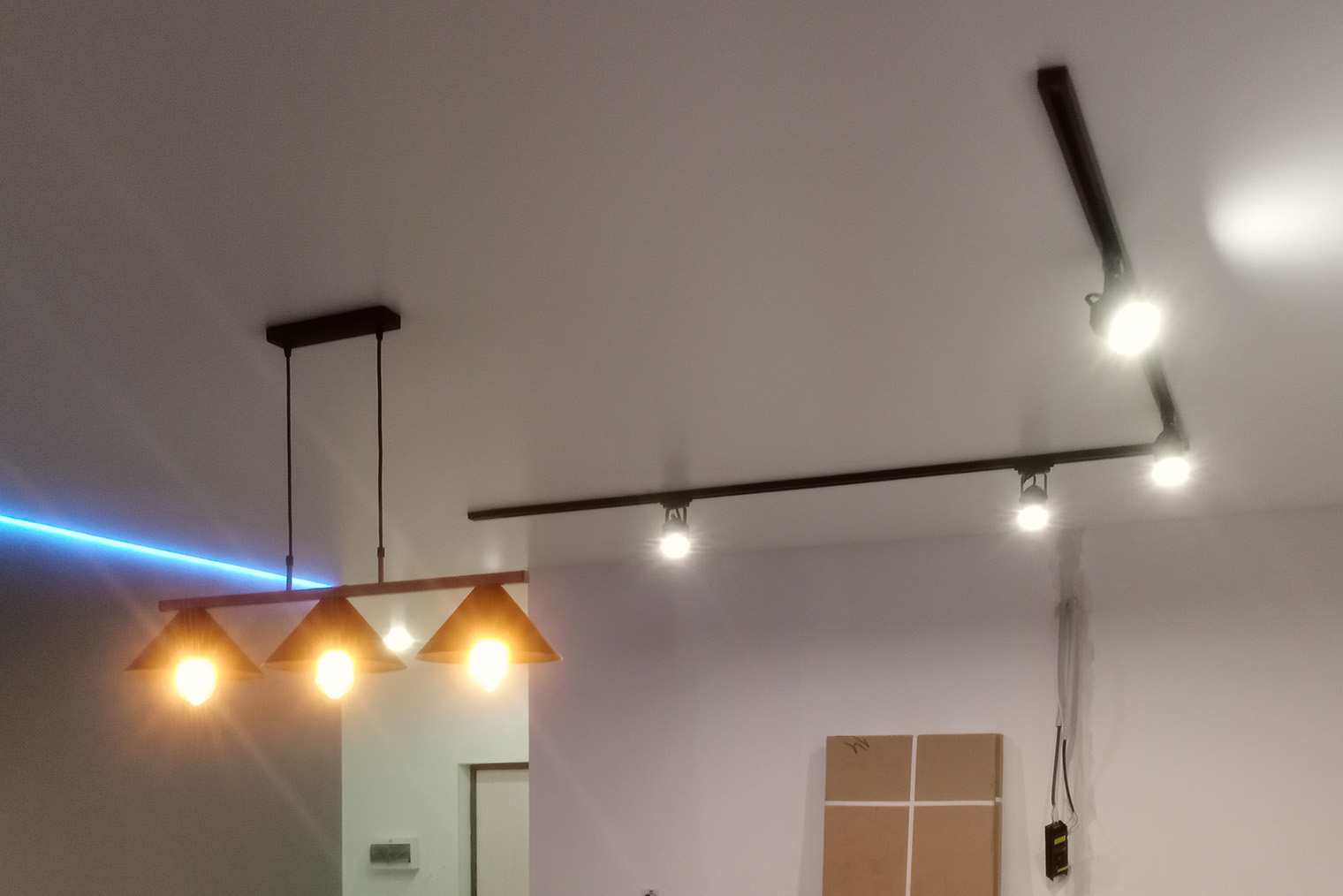 Парящий потолок позволяет совмещать разные виды освещения. Здесь используются трековые светильники, люстра и светодиодная лента. Фотография: Александр Хлыбов