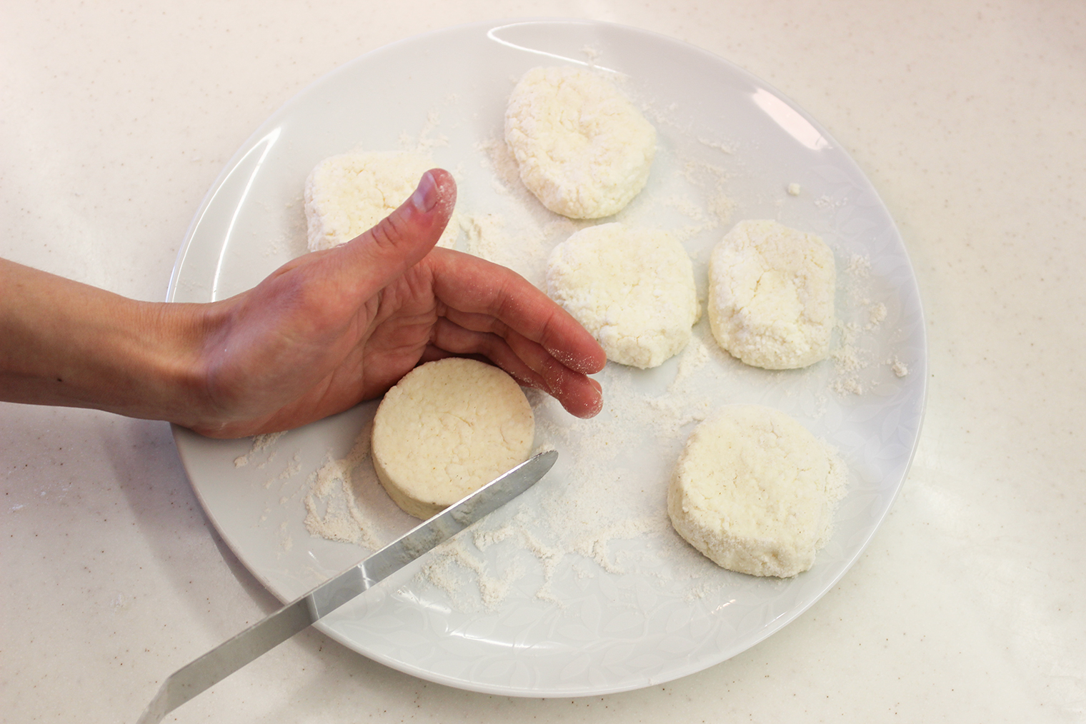 Согните ладонь с тестом в полукруг и подкручивайте заготовку шпателем против часовой стрелки. Важно сделать сырники одинаковой толщины, чтобы они равномерно прожарились