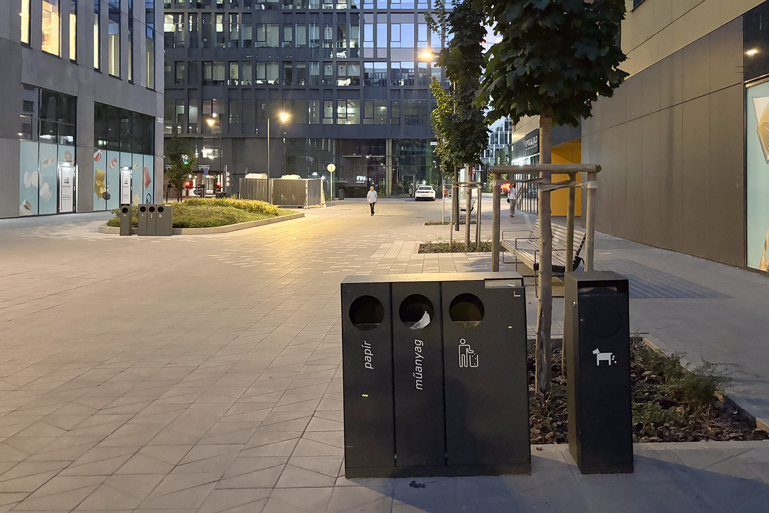 На фото видны четыре мусорных бака: для бумаги, пластика, прочих отходов и чуть поодаль — для собачьих отходов