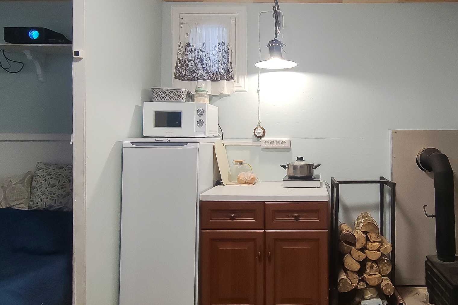 Напольный шкафчик на кухне симпатичный и функциональный. Слева видно, как стоит проектор в спальне
