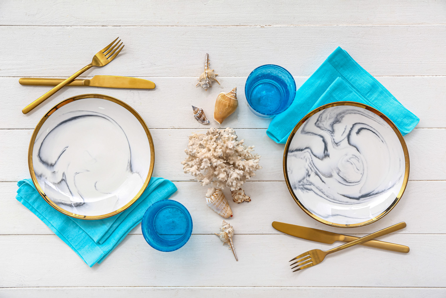 На столе в морском стиле появились столовые приборы золотистого цвета. Но главный цвет, синий, остался. Фотография: Pixel⁠-⁠Shot / Shutterstock / FOTODOM