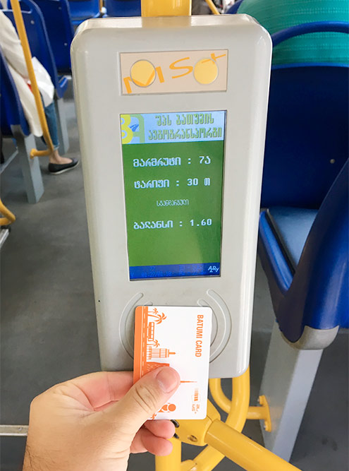 Для оплаты проезда в автобусе нужно приложить транспортную карту к терминалу у входа. На экране написано: маршрут 7а, тариф 30 тетри, баланс 1,6 лари