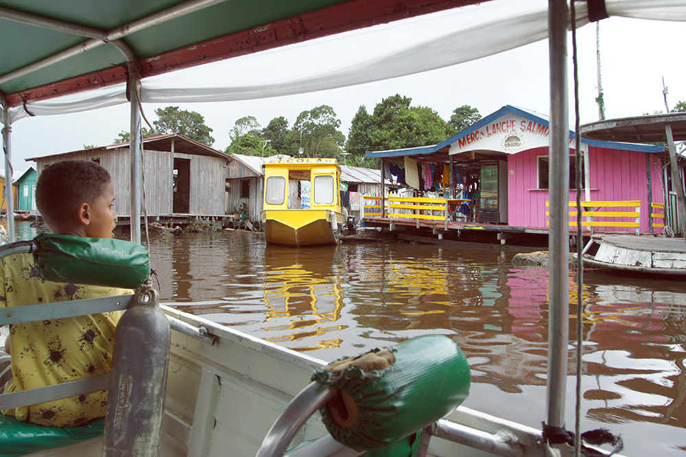 Поселение из плавучих домов в Амазонии. Желтая лодка — аналог школьного автобуса
