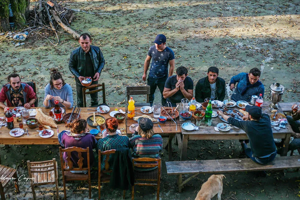 Волонтеры и гости из местных деревень обедают за общим столом