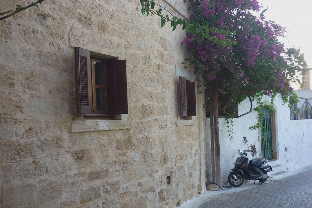 Это улица в нашей деревне Кутулуфари. Так выглядит настоящая Греция с узкими улочками в цветах. Дома в основном каменные или классические белые с синими дверями
