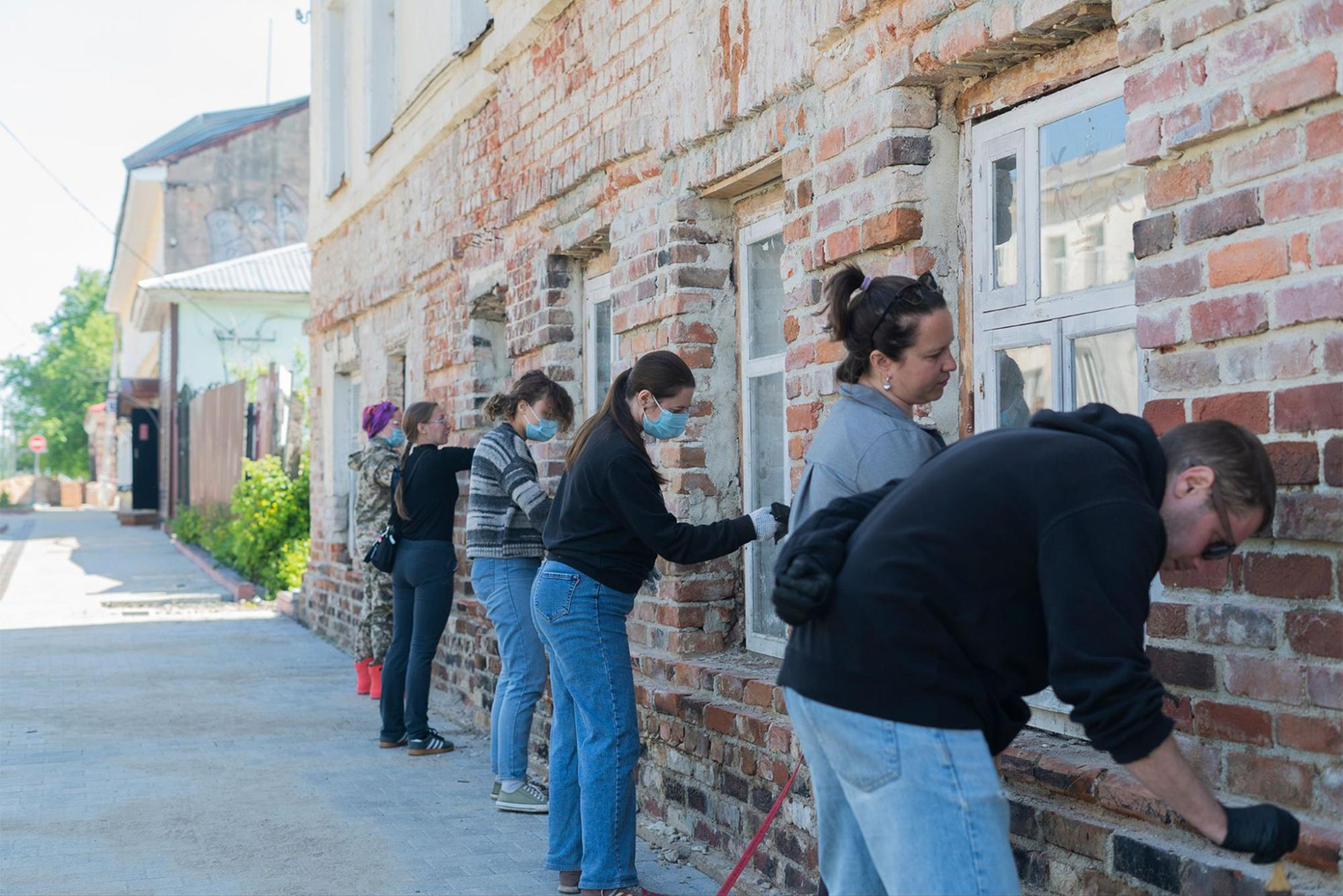 Волонтеры из проекта «Полезно путешествуй» расчищают фасад здания. 2023 г. Фотография: Дмитрий Андреев