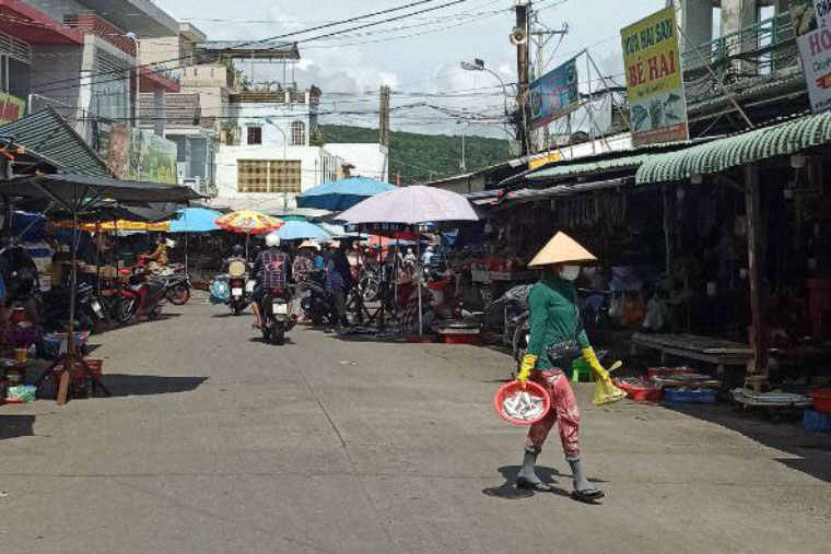 Вьетнамка идет по рынку под палящим солнцем