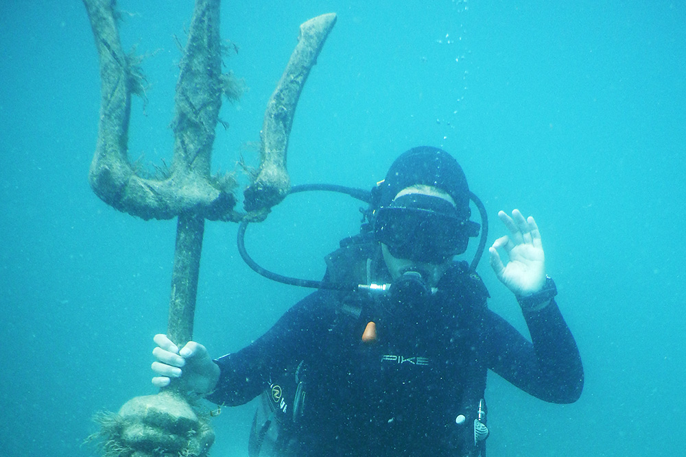 Погружение на Черном море. Одной рукой держусь за трезубец статуи в морском музее, другой — показываю, что у меня все хорошо