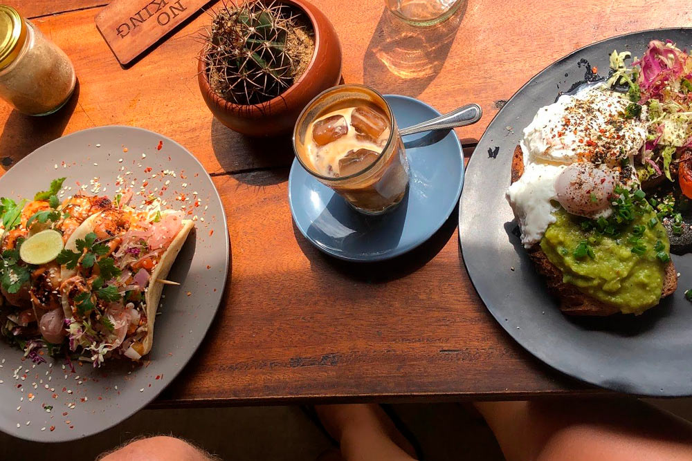 Завтрак с кофе, такос и тостом с авокадо в модном кафе