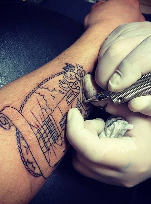 Татуировку маяка мастер начал с контуров