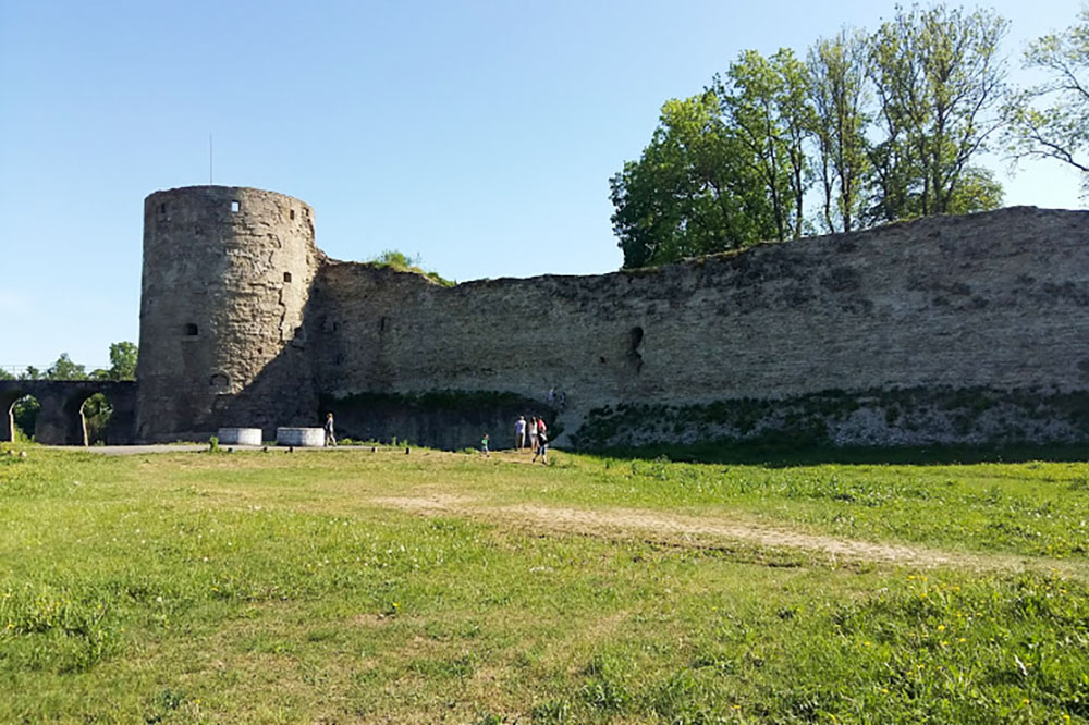 Крепость удобно обойти вокруг: по периметру нет рва с водой. Туристы смотрят на башни, мост и крепостные стены
