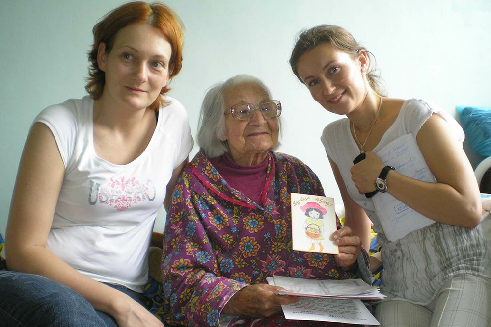 Волонтеры Женя и Маша вместе с бабушкой Машей рассматривают поздравительные открытки, которые ей пришли от волонтеров. Это отделение сестринского ухода Козловской больницы Тверской области, 2011 год