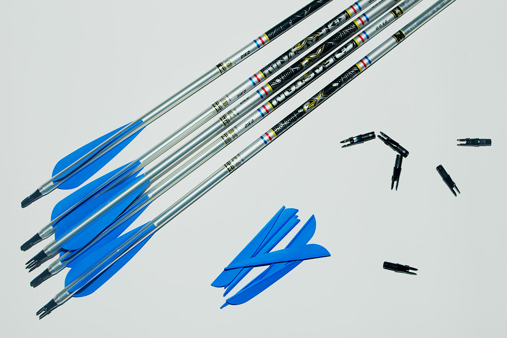 Слева на фото — хвост собранной стрелы. Справа — синие резиновые перья и черные хвостовики