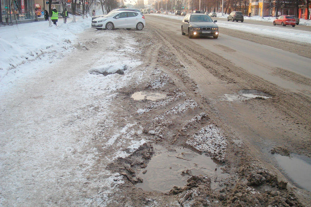 Это одна из основных магистралей Кемерова — проспект Ленина. Вдоль парковки оборудован небольшой тротуар, но зимой он завален снегом