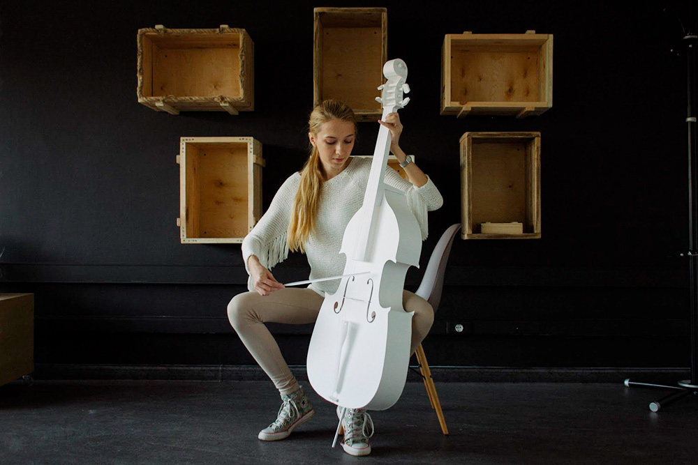 Александра позирует с бумажной виолончелью, которую заказали в подарок. Вместо струн — белые нити