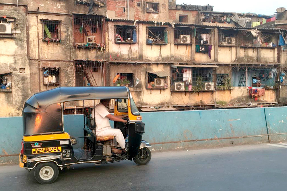 Рикша на фоне трущоб в Мумбаи. Рикшей называют и трехколесное транспортное средство, и водителя