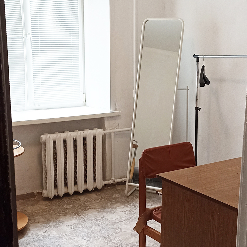 Правая сторона комнаты, вид из кухонной зоны: окно, зеркало, стол, стул, рейл для одежды