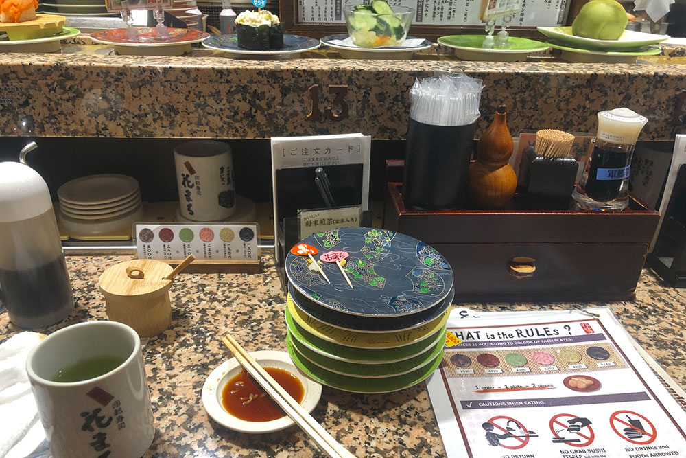 Поужинал в суши-баре с конвейерной лентой. Разные цвета тарелок обозначают разную стоимость блюд