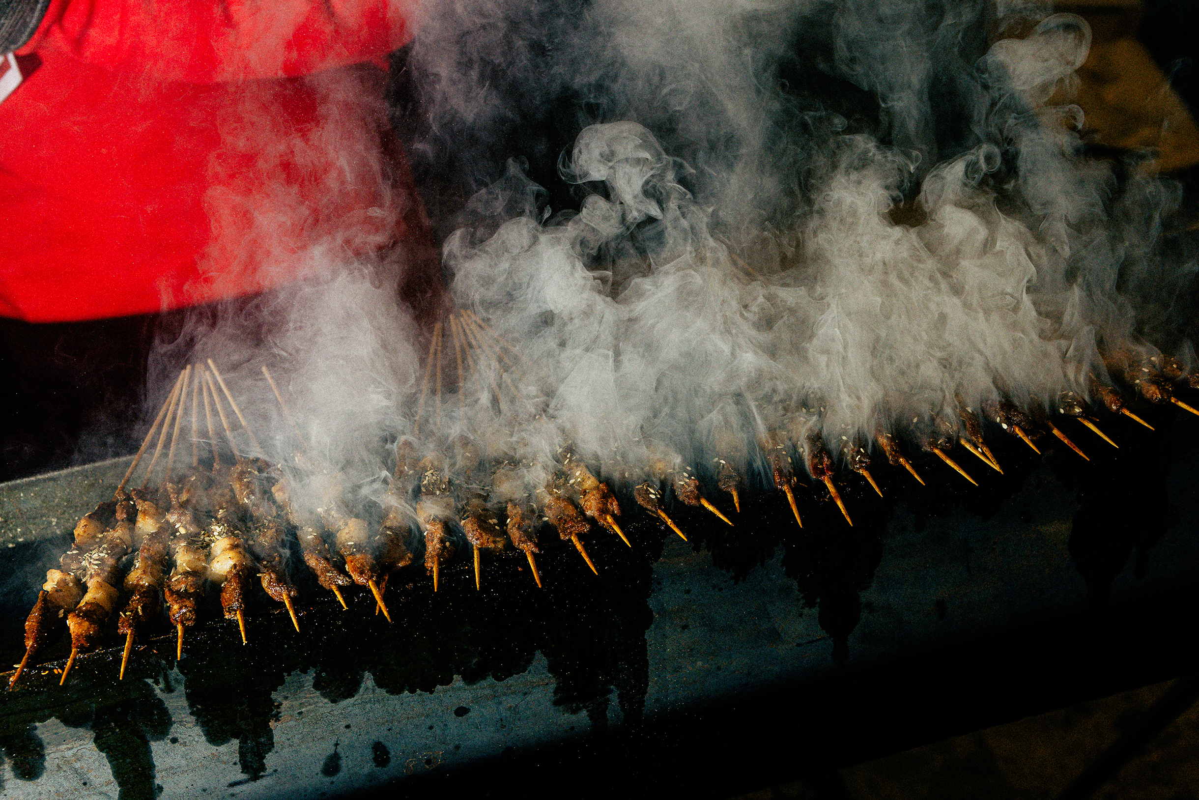 На прилавках — мясо и овощи на шпажках, колбаски, сладкие фрукты в карамели и другие угощения