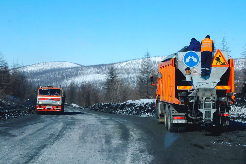 Дорожные рабочие отсыпают скользкие участки трассы шлаком — твердыми остатками от сжигания угля