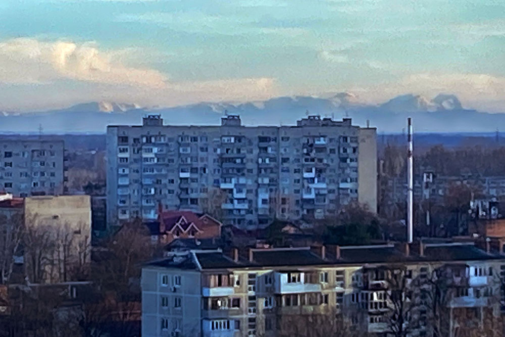 В ясную погоду над домами, как облака, виднеются Кавказские горы