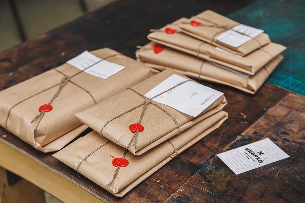 Есть два вида упаковки: базовая из бумаги и подарочная деревянная, которую нужно покупать отдельно. Вместе с изделием в упаковку часто кладут брошюру с рекламой компании, подарок или талон на скидку. На фото последовательность упаковки кошелька вплоть до отправки его на почте
