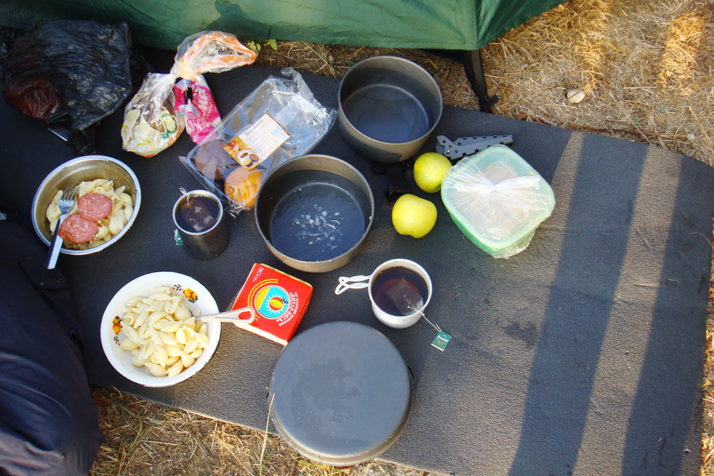 Типичный походный ужин: макароны с колбасой, хлеб и сыр. На десерт — чай с кексами и яблоки